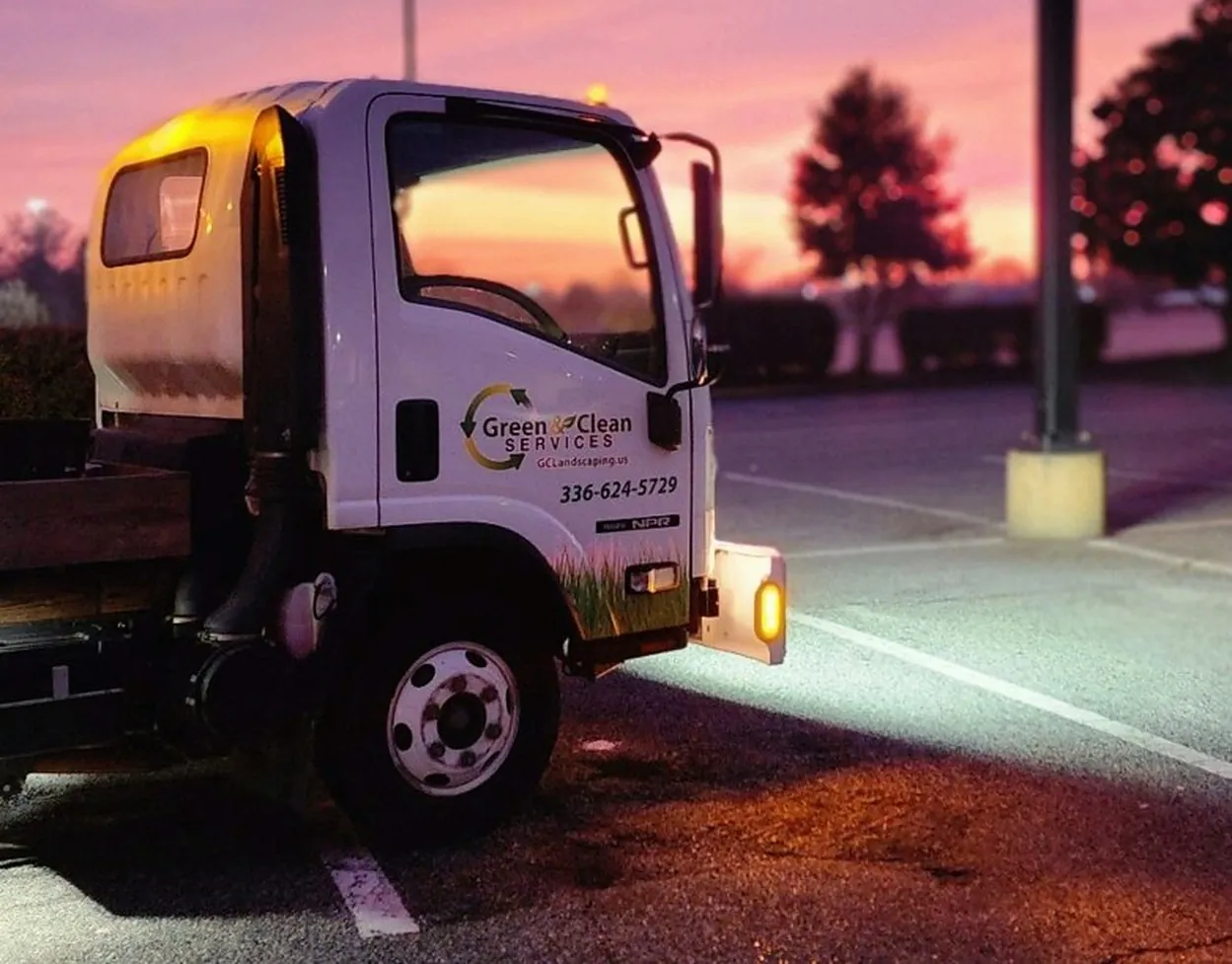 Green & Clean sweeper truck parked in a commercial lot at sunset